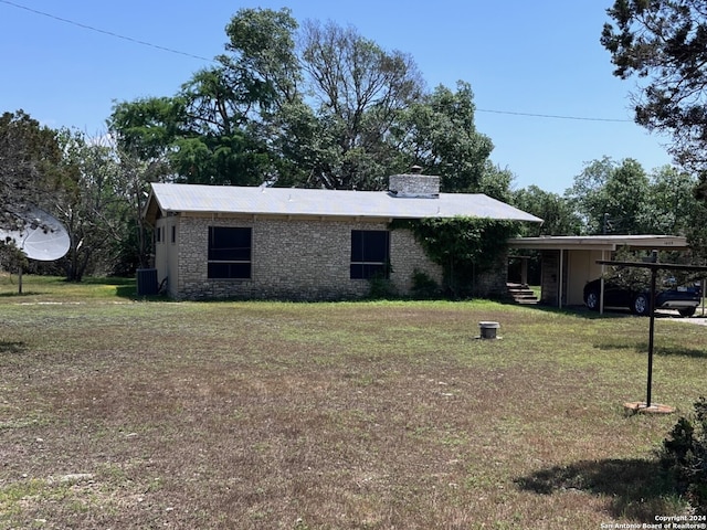 rear view of house with a carport, a yard, and central air condition unit