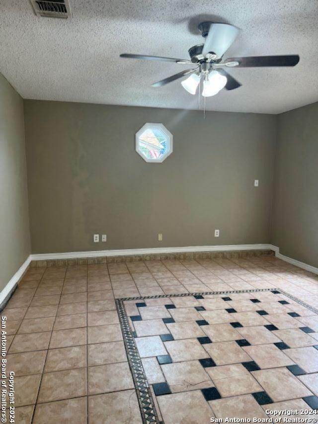 tiled spare room featuring ceiling fan and a textured ceiling