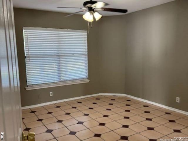 tiled spare room with ceiling fan