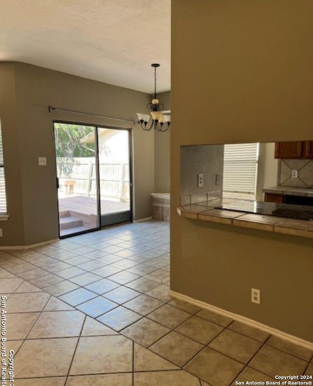 kitchen with a notable chandelier, backsplash, tile countertops, pendant lighting, and light tile floors