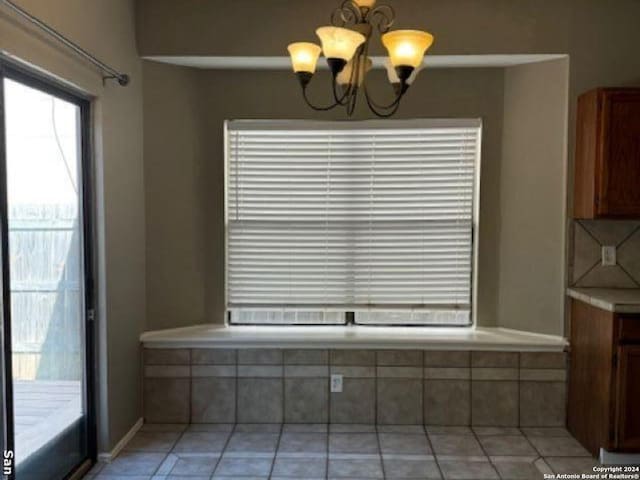 unfurnished dining area with a chandelier and light tile floors