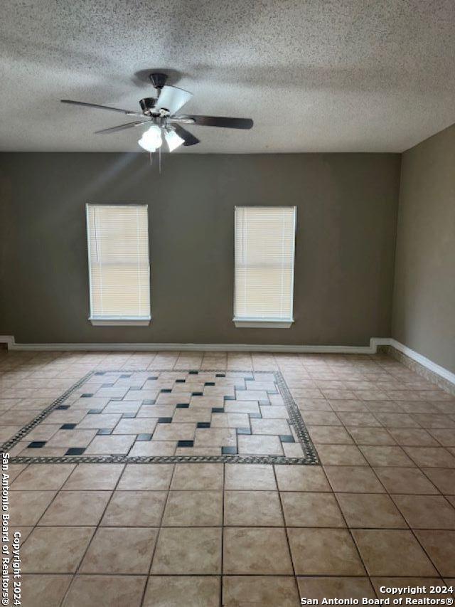 tiled spare room with ceiling fan and a textured ceiling