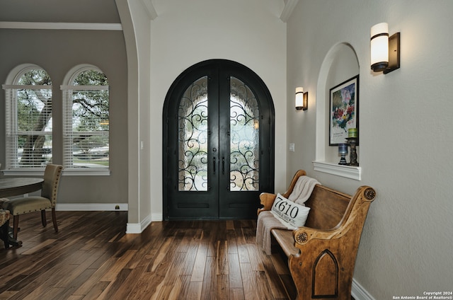 entrance foyer with crown molding, dark wood-type flooring, and french doors