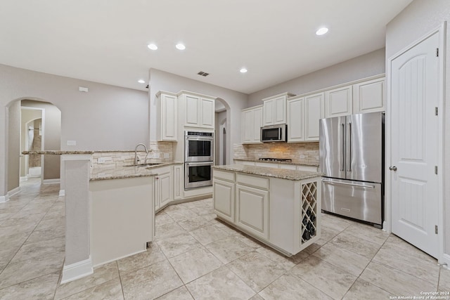 kitchen with sink, light tile floors, stainless steel appliances, and light stone countertops