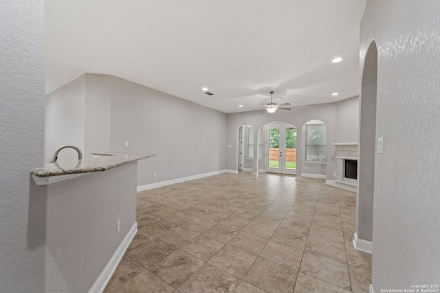 unfurnished living room featuring ceiling fan and light tile floors