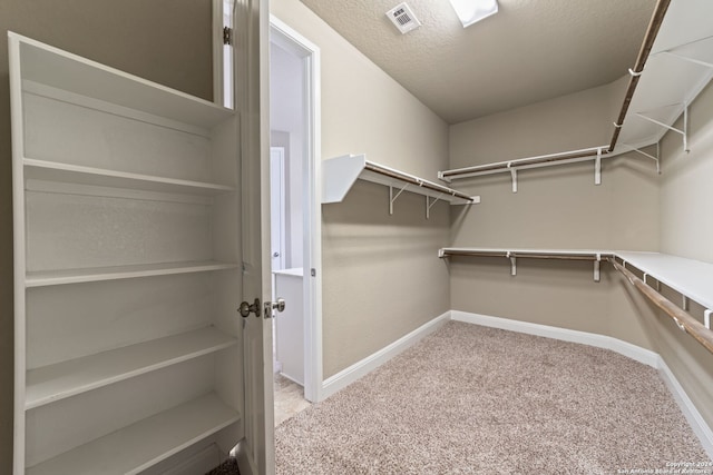 walk in closet featuring light carpet