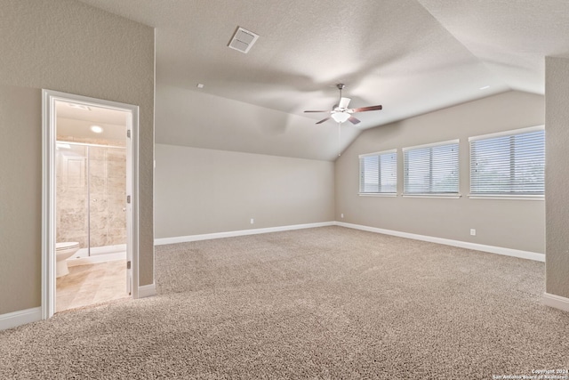 empty room with carpet floors, a textured ceiling, ceiling fan, and vaulted ceiling