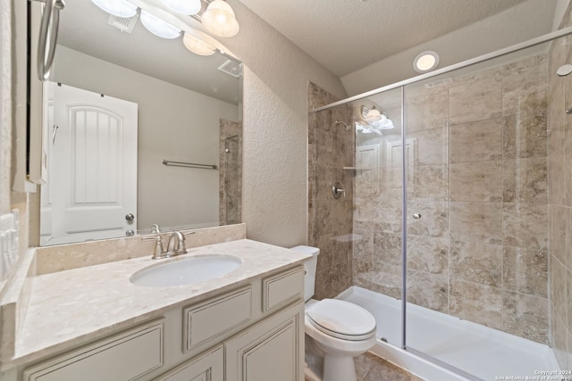 bathroom featuring tile flooring, vanity with extensive cabinet space, a textured ceiling, toilet, and a shower with door