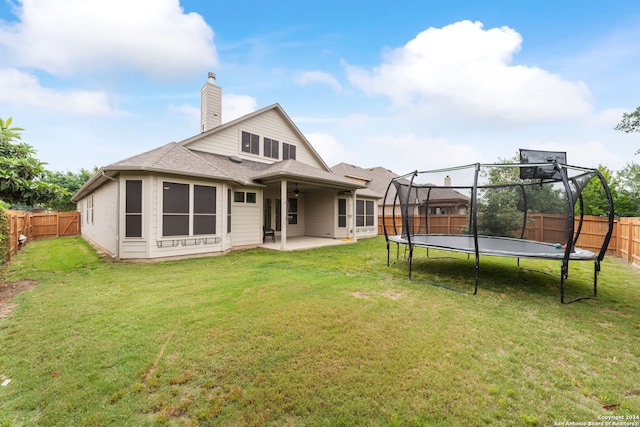 back of property featuring a trampoline, a lawn, and a patio area