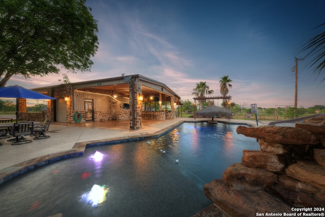 pool at dusk featuring a patio area