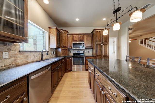 kitchen with decorative light fixtures, appliances with stainless steel finishes, tasteful backsplash, sink, and light wood-type flooring