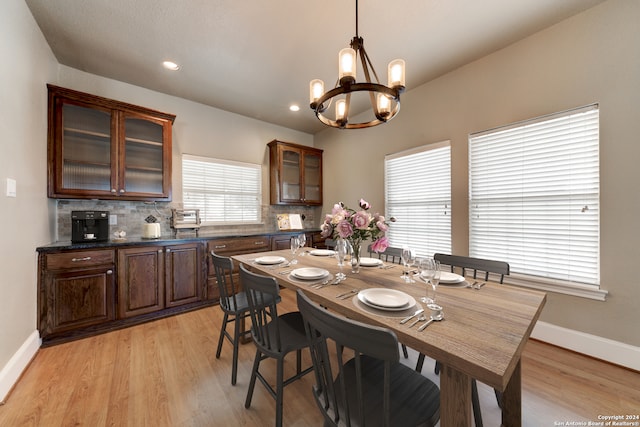 dining area with light hardwood / wood-style floors and a chandelier