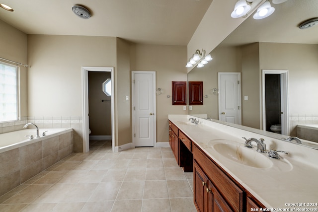 bathroom with large vanity, tiled tub, double sink, tile floors, and toilet