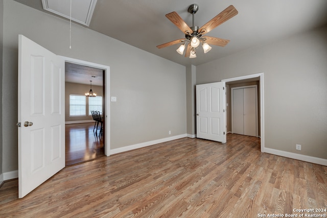 unfurnished bedroom with hardwood / wood-style floors and ceiling fan with notable chandelier