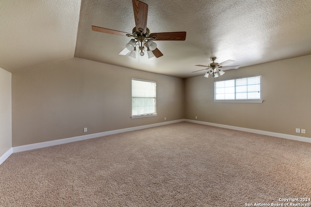 carpeted spare room featuring vaulted ceiling, ceiling fan, a wealth of natural light, and a textured ceiling