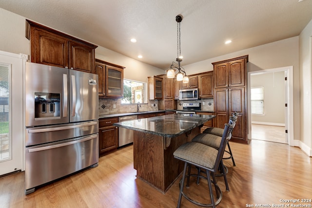 kitchen featuring a center island, stainless steel appliances, light hardwood / wood-style floors, and tasteful backsplash