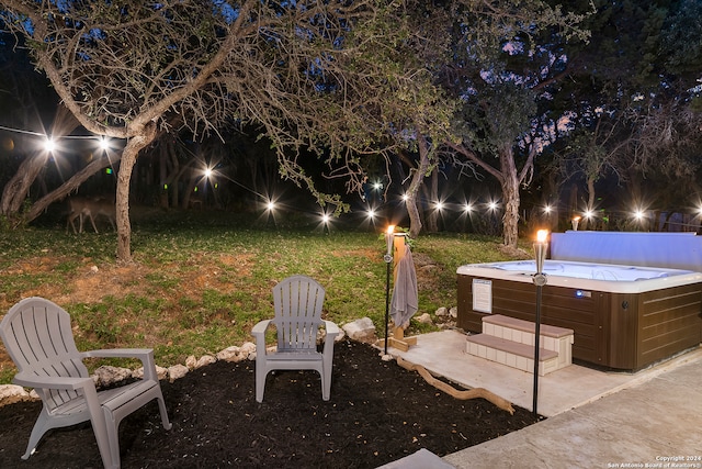 yard at night featuring a hot tub