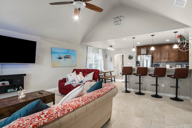 tiled living room with ceiling fan and high vaulted ceiling