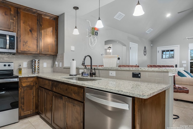 kitchen with appliances with stainless steel finishes, kitchen peninsula, tasteful backsplash, and lofted ceiling