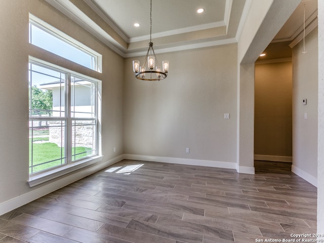 spare room with a raised ceiling, hardwood / wood-style floors, and a notable chandelier