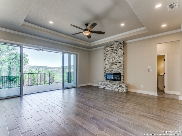 unfurnished living room with ceiling fan, a wealth of natural light, a fireplace, and a tray ceiling