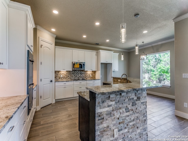 kitchen with pendant lighting, ornamental molding, light stone counters, tasteful backsplash, and a textured ceiling