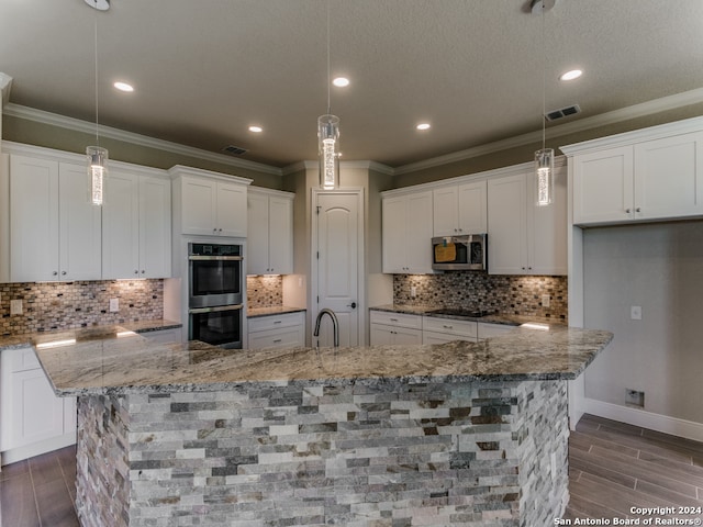 kitchen featuring appliances with stainless steel finishes, tasteful backsplash, pendant lighting, and a large island with sink