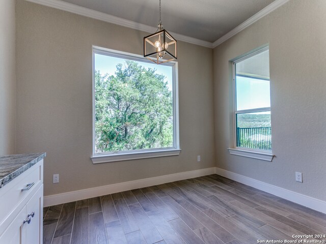 unfurnished dining area featuring hardwood / wood-style flooring, an inviting chandelier, and ornamental molding