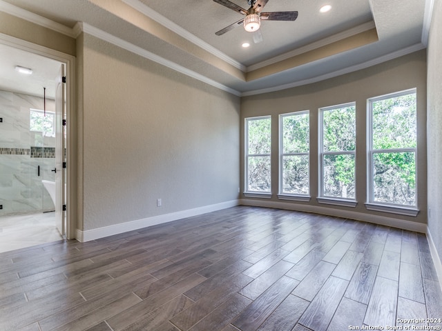 spare room with dark hardwood / wood-style floors, a tray ceiling, ornamental molding, ceiling fan, and a textured ceiling