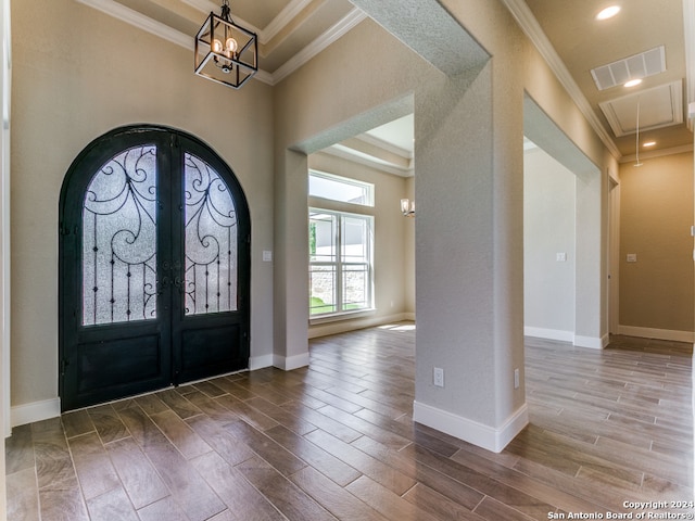 entrance foyer featuring wood-type flooring, french doors, crown molding, and an inviting chandelier