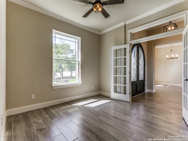 empty room with ceiling fan with notable chandelier, hardwood / wood-style floors, french doors, and ornamental molding