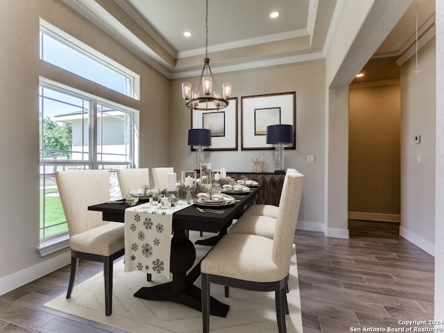 dining area featuring ornamental molding, dark hardwood / wood-style flooring, a tray ceiling, and a notable chandelier