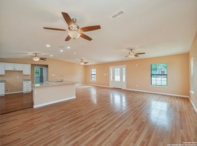 unfurnished living room with french doors, ceiling fan, sink, and light wood-type flooring