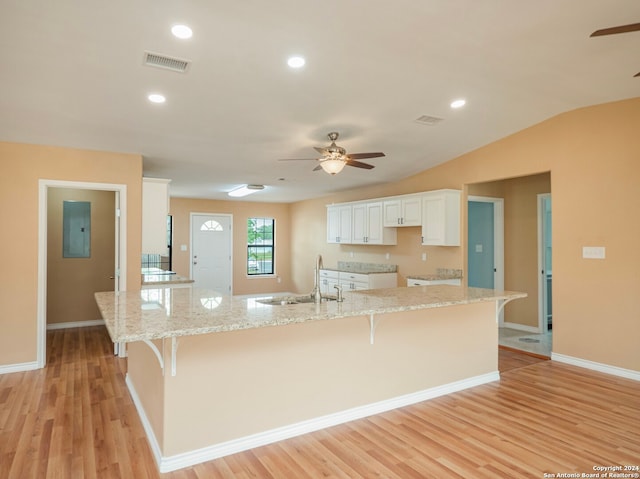 kitchen featuring light hardwood / wood-style flooring, ceiling fan, a kitchen island with sink, white cabinets, and a kitchen breakfast bar