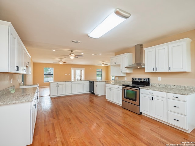 kitchen featuring ceiling fan, wall chimney exhaust hood, light hardwood / wood-style floors, white cabinetry, and stainless steel electric stove