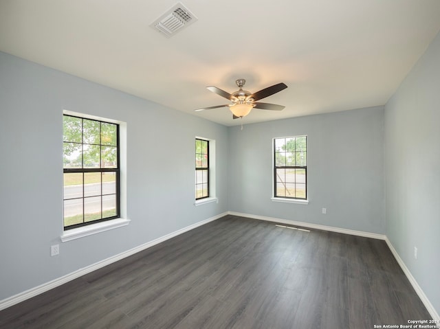 empty room featuring dark hardwood / wood-style floors, a wealth of natural light, and ceiling fan