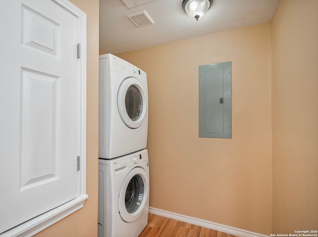 clothes washing area with light wood-type flooring and stacked washing maching and dryer