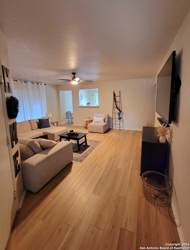 living room with light hardwood / wood-style flooring, ceiling fan, and a textured ceiling