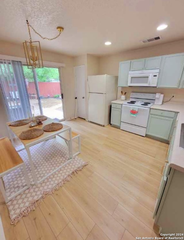 kitchen with hanging light fixtures, light hardwood / wood-style flooring, and white appliances