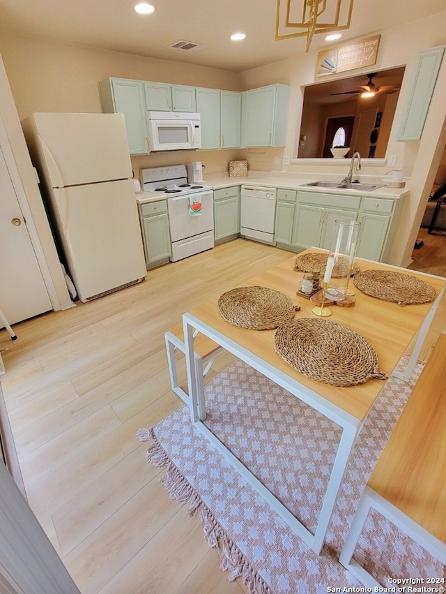 kitchen with light hardwood / wood-style flooring, white appliances, sink, and green cabinetry