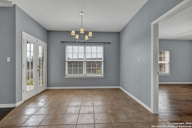 tiled empty room with french doors and a notable chandelier