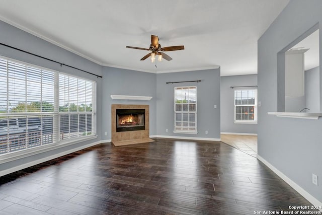 unfurnished living room with ornamental molding, wood-type flooring, ceiling fan, and a tile fireplace