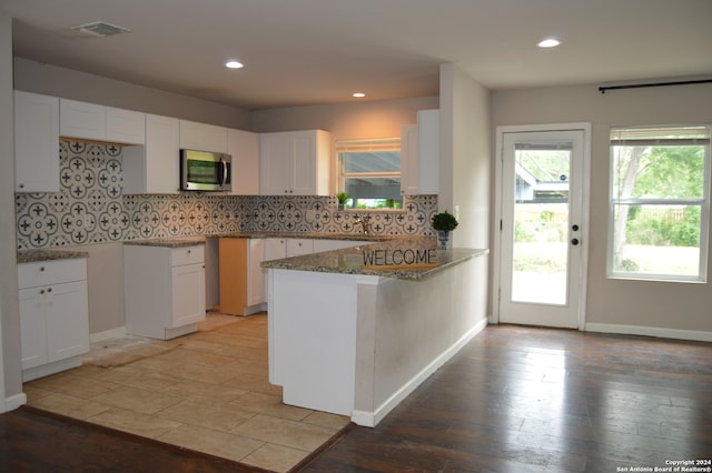 kitchen featuring tasteful backsplash, kitchen peninsula, and white cabinetry