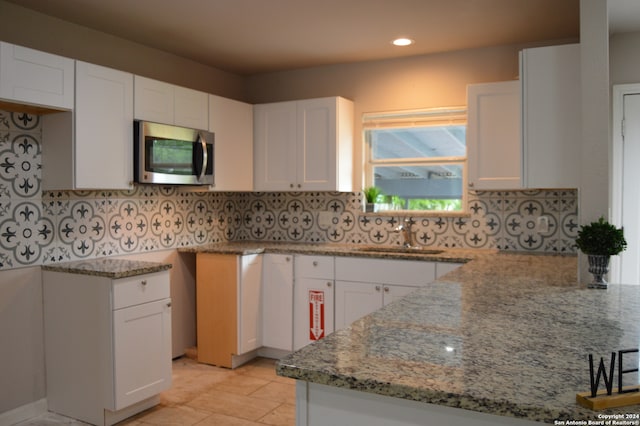 kitchen with sink, tasteful backsplash, and white cabinetry