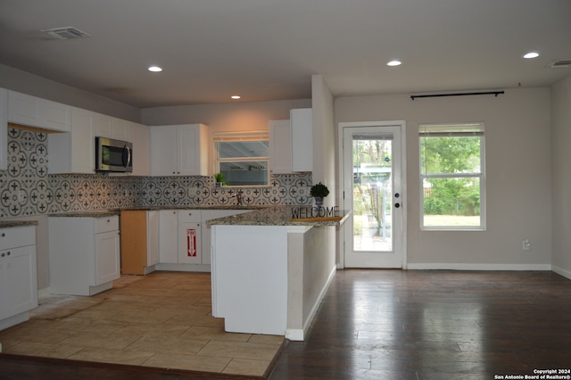 kitchen with backsplash, light stone countertops, a center island, and white cabinets