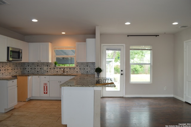 kitchen with tasteful backsplash, light hardwood / wood-style flooring, white cabinetry, and light stone counters