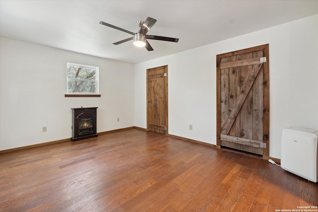 unfurnished living room with hardwood / wood-style floors, ceiling fan, and a wood stove