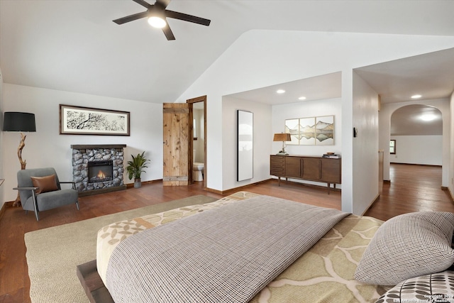 bedroom featuring a fireplace, ensuite bath, dark hardwood / wood-style floors, ceiling fan, and lofted ceiling