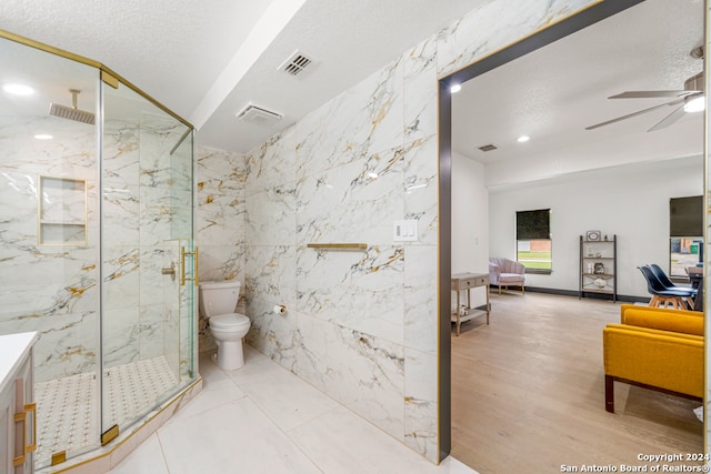 bathroom with tile walls, hardwood / wood-style floors, a shower with shower door, toilet, and ceiling fan