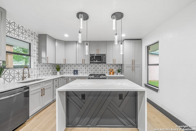 kitchen with tasteful backsplash, stainless steel appliances, light wood-type flooring, and pendant lighting